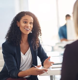 Interview with a happy, excited and confident human resources manager talking to a shortlist candidate for a job. Young business woman meeting with a colleague or coworker in her office at work.
